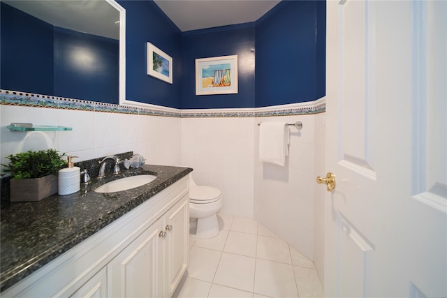 bathroom with tile patterned floors, a wainscoted wall, toilet, tile walls, and vanity