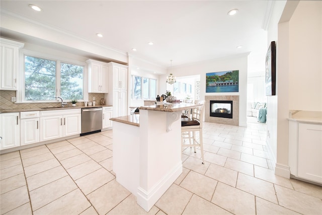 kitchen featuring dishwasher, a breakfast bar, light tile patterned floors, decorative backsplash, and white cabinetry