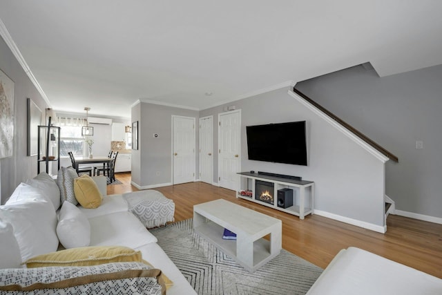 living area featuring ornamental molding, a wall mounted AC, and wood finished floors