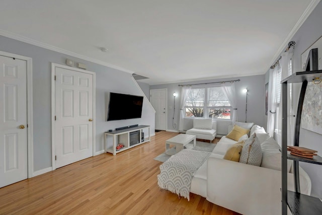 living area with crown molding, light wood-style floors, and baseboards