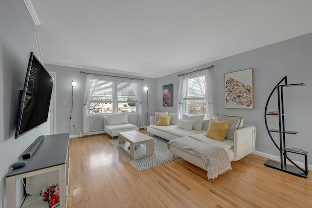 living room featuring baseboard heating, crown molding, light wood-type flooring, and baseboards