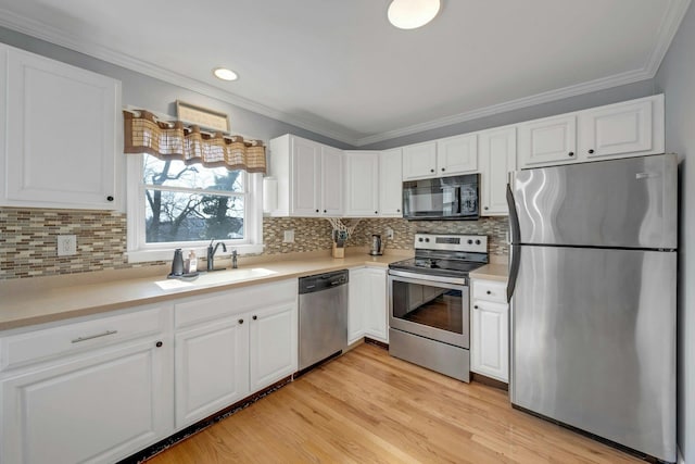 kitchen featuring a sink, crown molding, white cabinets, and stainless steel appliances