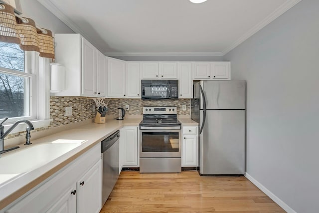 kitchen with light wood-style flooring, white cabinets, appliances with stainless steel finishes, and ornamental molding