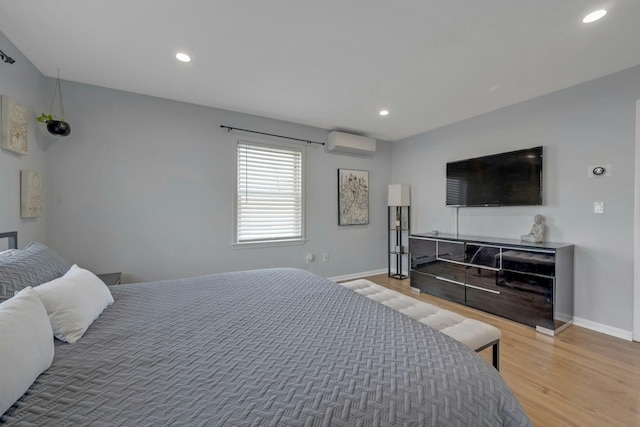 bedroom featuring a wall mounted air conditioner, baseboards, wood finished floors, and recessed lighting