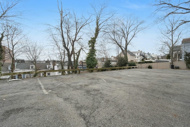 uncovered parking lot featuring a residential view and fence