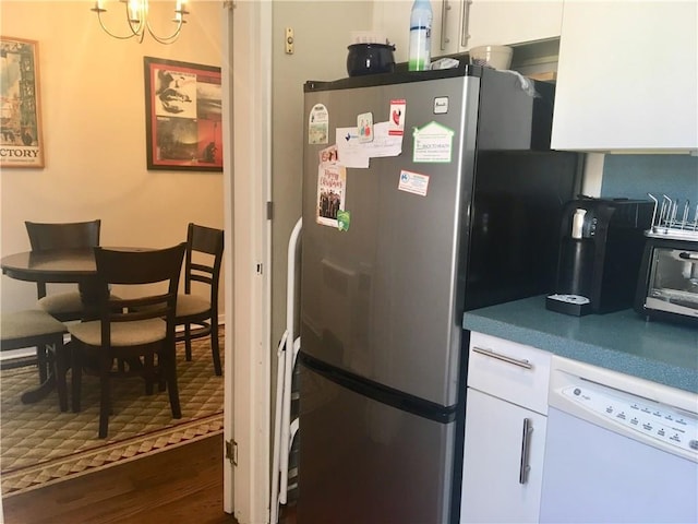 kitchen featuring freestanding refrigerator, white dishwasher, a notable chandelier, white cabinets, and dark wood-style flooring