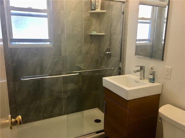 full bath featuring toilet, vanity, and a tile shower