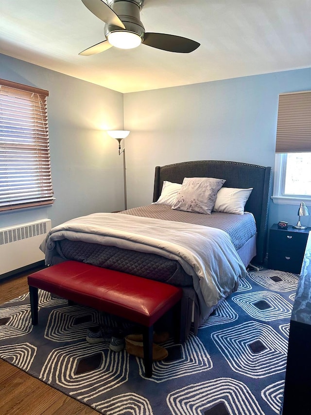 bedroom featuring radiator heating unit, ceiling fan, and wood finished floors