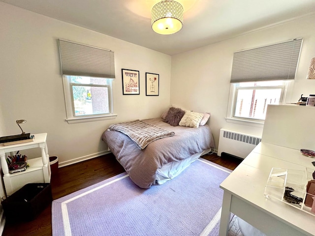 bedroom featuring multiple windows, radiator, and wood finished floors