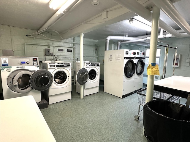 community laundry room with washer and clothes dryer, tile patterned floors, and concrete block wall