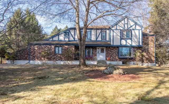 tudor house featuring brick siding and a front yard