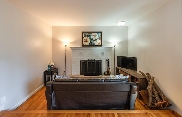 living room featuring baseboards, wood finished floors, and a fireplace