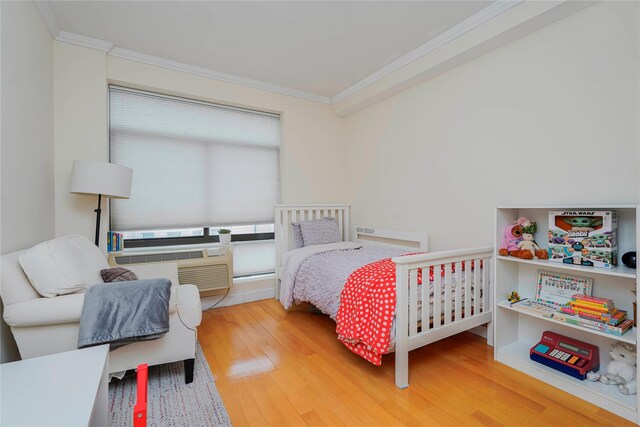 bedroom featuring a wall mounted AC, crown molding, and wood finished floors