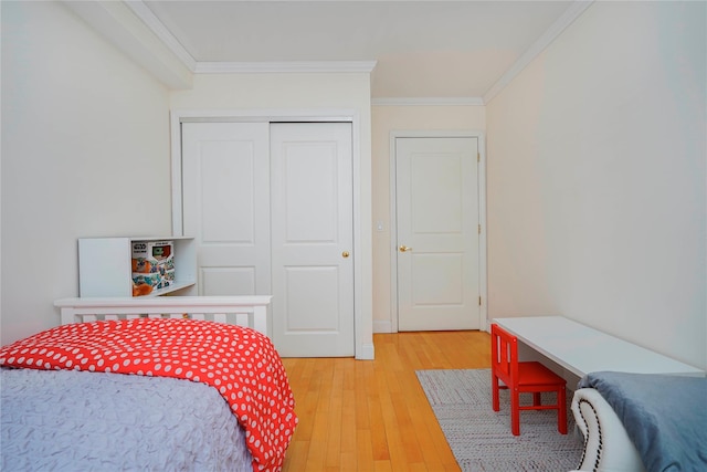 bedroom with a closet, light wood-style floors, and crown molding