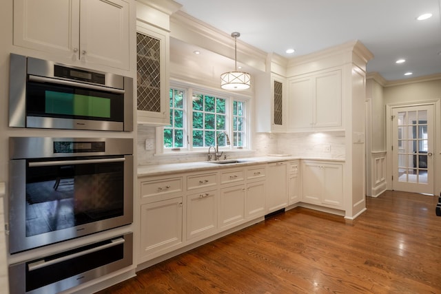 kitchen featuring paneled dishwasher, a sink, light countertops, a warming drawer, and tasteful backsplash