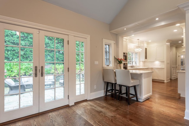 kitchen with backsplash, dark wood finished floors, white cabinets, light countertops, and lofted ceiling