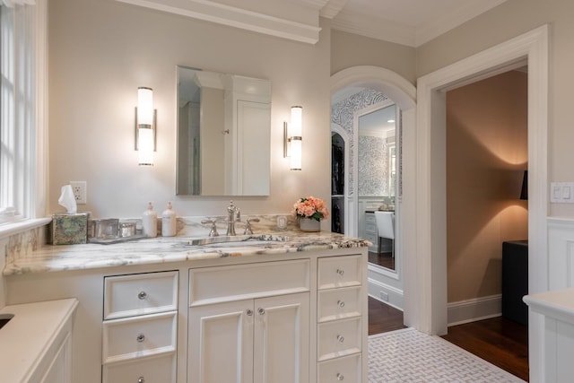 bathroom featuring vanity, crown molding, wood finished floors, and baseboards