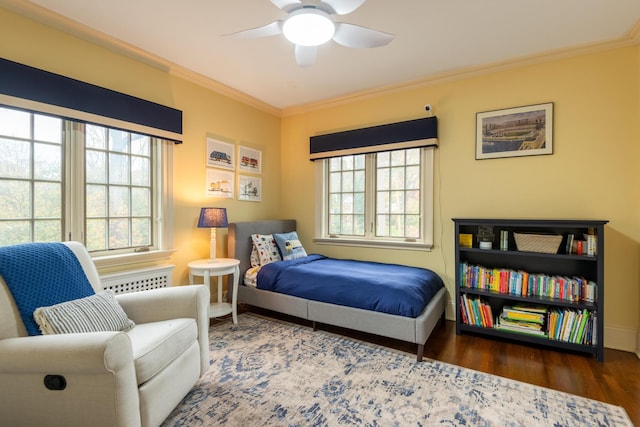 bedroom with baseboards, multiple windows, wood finished floors, and crown molding