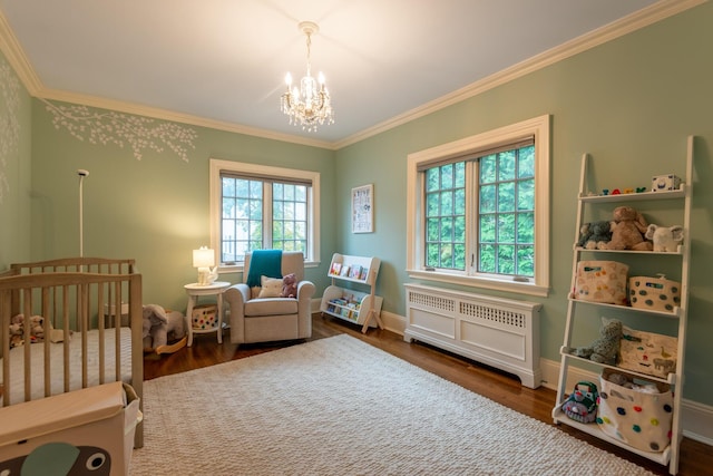 bedroom featuring a chandelier, ornamental molding, a nursery area, and wood finished floors