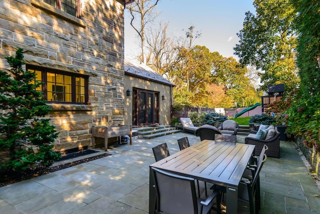 view of patio with outdoor dining space, a playground, and fence