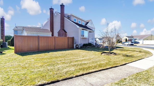 view of side of property with a lawn, central AC unit, a chimney, and fence