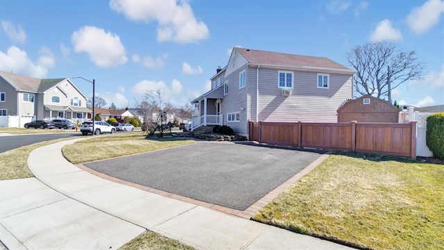 view of property exterior featuring a residential view, a lawn, and fence