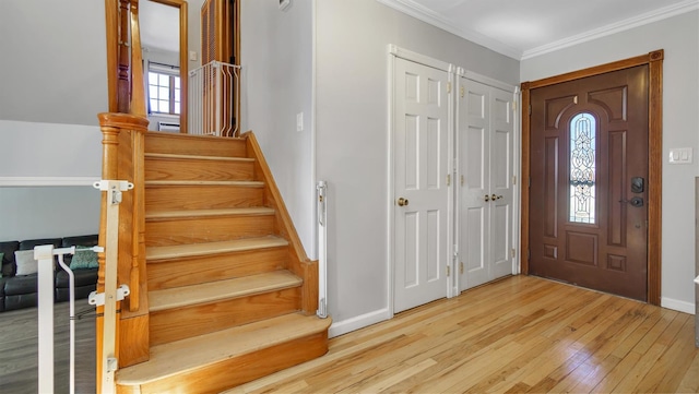 entrance foyer with baseboards, wood finished floors, stairs, and crown molding