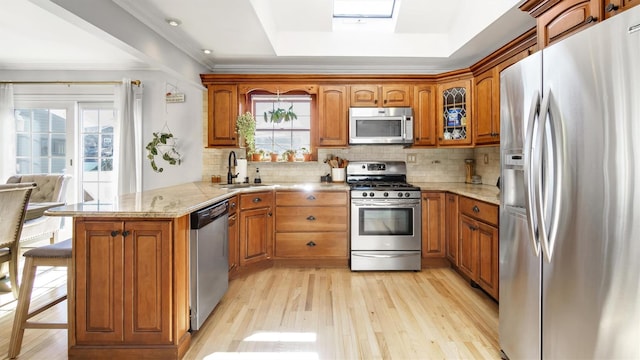 kitchen with a sink, brown cabinetry, a wealth of natural light, and stainless steel appliances