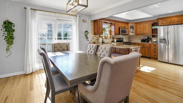 dining space with crown molding, baseboards, and light wood finished floors