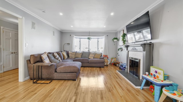 living area featuring recessed lighting, wood finished floors, a fireplace, and crown molding