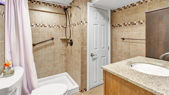 bathroom with toilet, tile walls, a shower stall, tile patterned flooring, and vanity