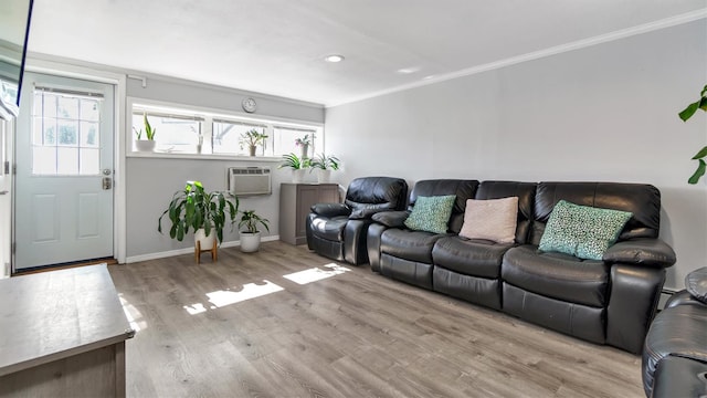 living area with crown molding, wood finished floors, a wall mounted air conditioner, and a healthy amount of sunlight