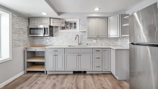 kitchen featuring a sink, open shelves, gray cabinets, and stainless steel appliances