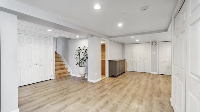 finished below grade area with stairway, recessed lighting, light wood-style floors, and baseboards