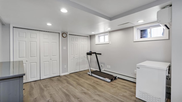 exercise room featuring recessed lighting, a baseboard heating unit, and light wood finished floors