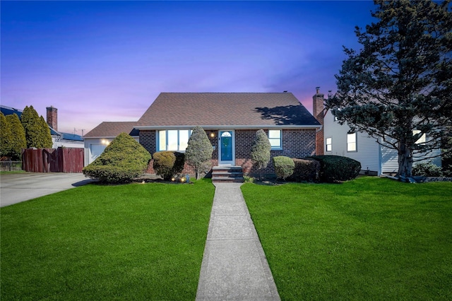 view of front of home featuring brick siding, a shingled roof, a front yard, and fence