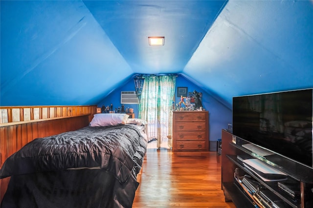 bedroom with lofted ceiling, wood finished floors, and a wall mounted AC