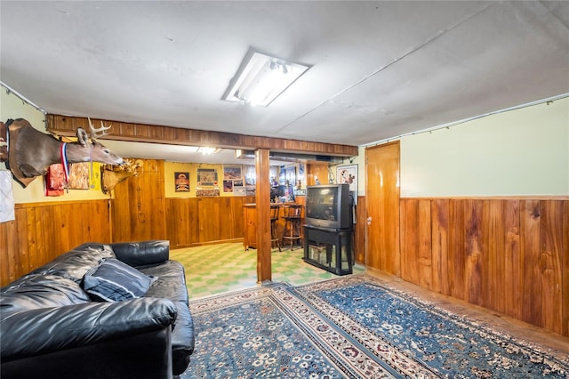 living room with tile patterned floors, wooden walls, and a wainscoted wall