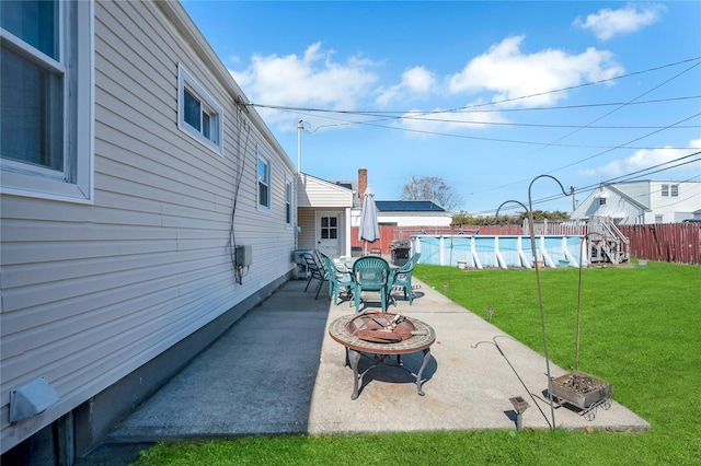 view of patio with a fenced in pool, a fire pit, and fence