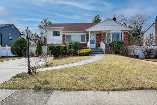 view of front of property featuring brick siding, a chimney, a front lawn, and fence