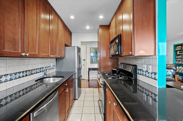 kitchen with brown cabinets, a sink, stainless steel appliances, light tile patterned floors, and decorative backsplash