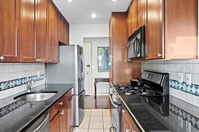 kitchen featuring a sink, brown cabinets, appliances with stainless steel finishes, and dark stone countertops