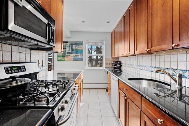 kitchen with baseboard heating, tasteful backsplash, appliances with stainless steel finishes, and a sink