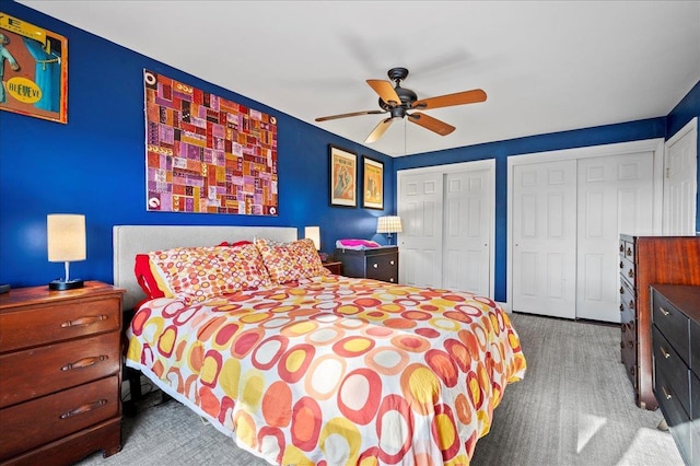 bedroom with two closets, ceiling fan, and carpet flooring