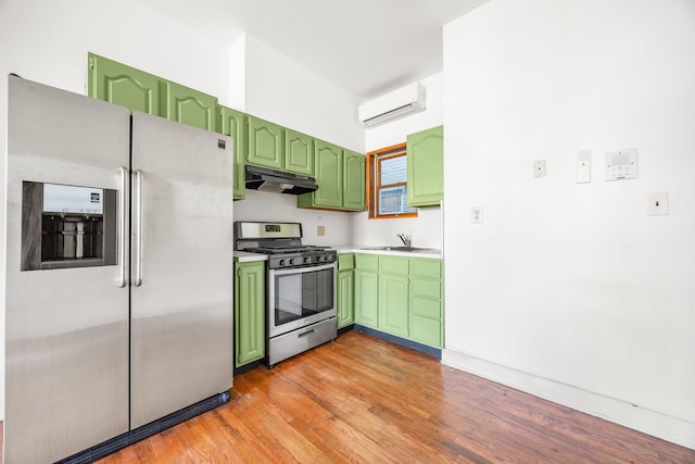 kitchen with green cabinets, a wall mounted air conditioner, under cabinet range hood, and stainless steel appliances