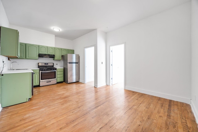 kitchen featuring a sink, stainless steel appliances, green cabinets, light wood finished floors, and light countertops