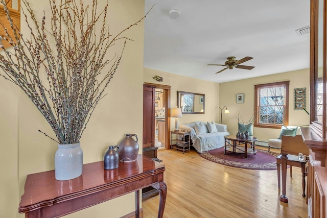 living room featuring visible vents, light wood-type flooring, and ceiling fan