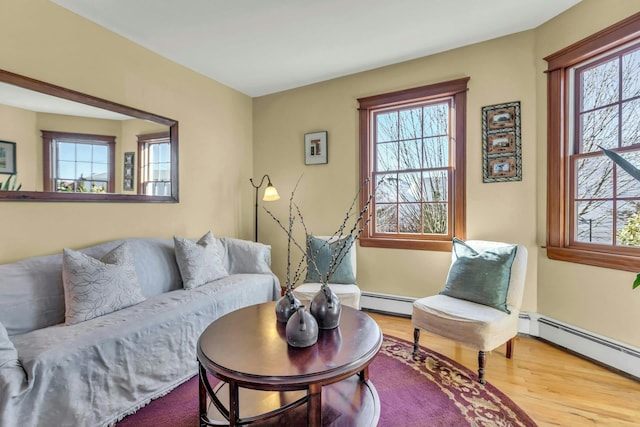 living room with a baseboard radiator, plenty of natural light, and wood finished floors