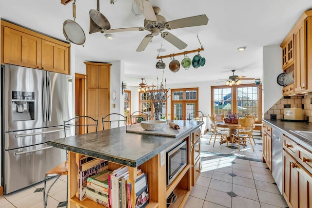 kitchen with light tile patterned floors, open shelves, appliances with stainless steel finishes, dark countertops, and tasteful backsplash