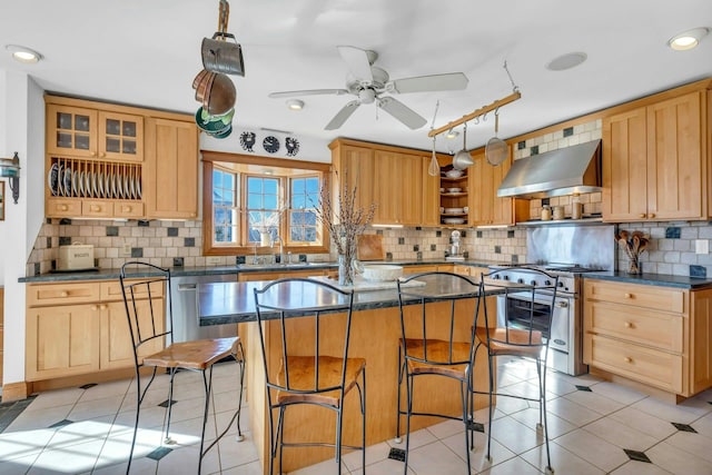 kitchen with backsplash, a kitchen island, wall chimney range hood, a breakfast bar area, and appliances with stainless steel finishes